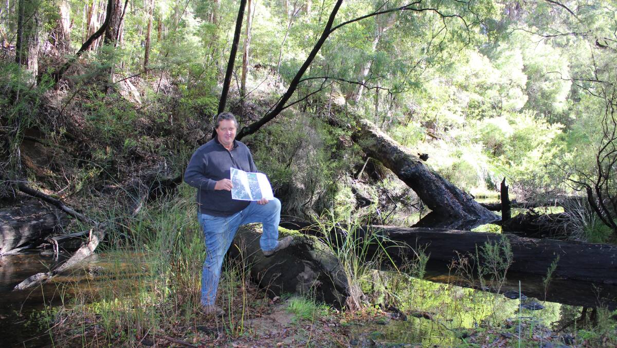  John Kilrain, a Manjimup landowner opposed to the Southern Forests Irrigation Scheme, holding a map of the proposed scheme water pipeline distribution network, in an area of the Donnelly River proposed to be inundated behind a four-metre high weir so up to 15,000 megalitres of winter stream flow a year can be pumped into a storage dam to be built in a Donnelly State Forest gully above the river.