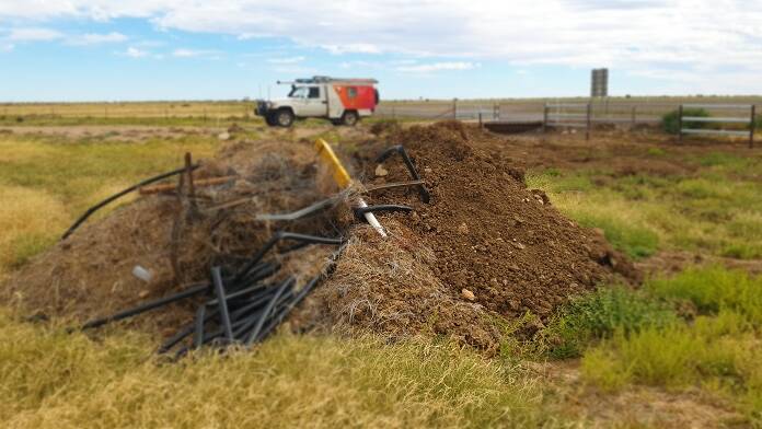 A fibre optic marker post and conduit cable mixed up with a pile of dirt alongside the Flinders Highway.