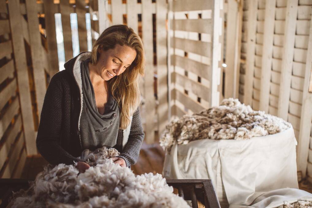 Wool master classer and professional photographer Chantel McAlister, wearing Merino wool and inspecting a fleece for a shot promoting her The Truth About Wool campaign. Picture: The Real Deal Photography