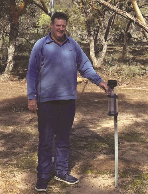 Grower Rod Birch checking the rain gauge at his Marchagee property.