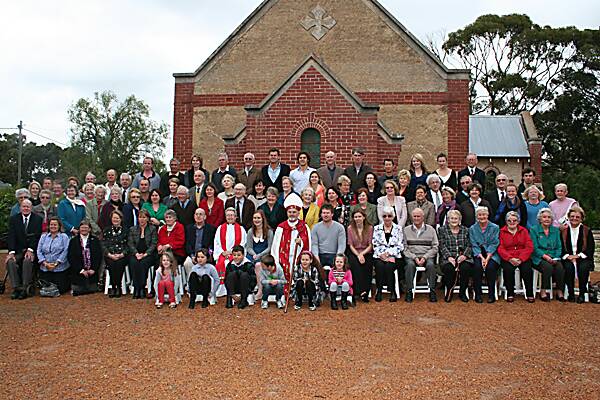 The congregation gathers in front of St Mark’s Anglican Church, Tammin after its 80th anniversary service. Amy Bachelor, who was confirmed at the service, is sitting between Bishop Tom Wilmot and Reverend Carol Whitcombe.