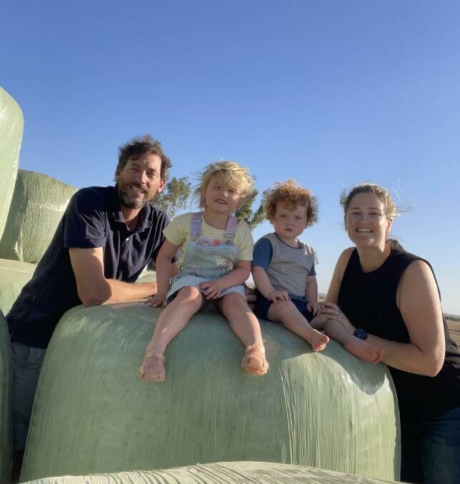 West Coorow beef producers, Steele and Laura Rudd, sit on one of their hay bales, with their two children, Eleanor, 3, and George, 1.