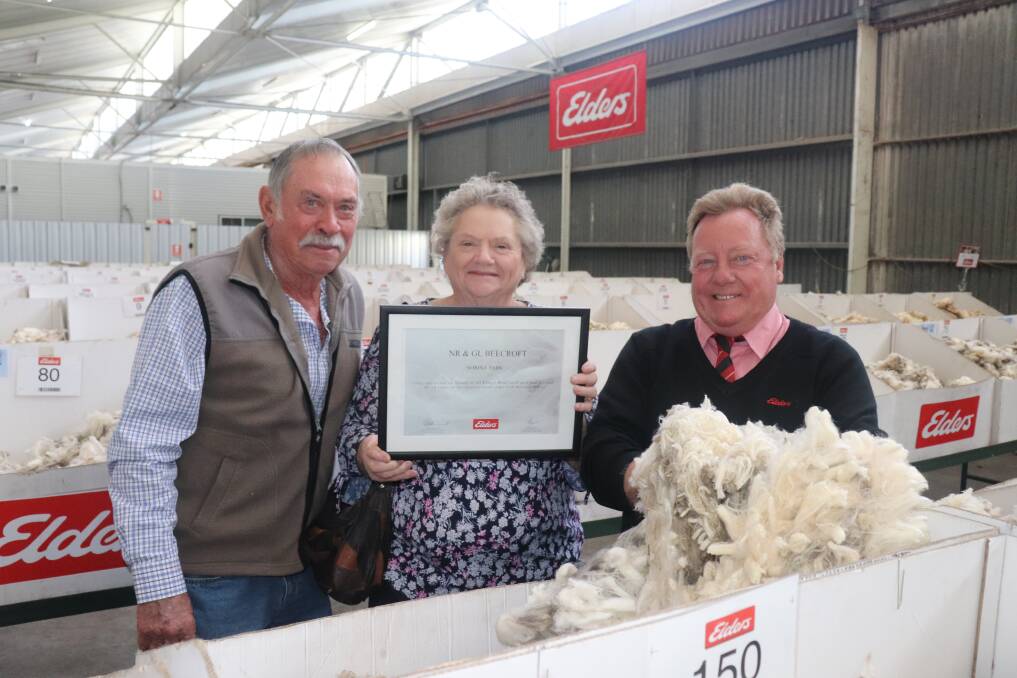 Woolgrowers Norm (left) and Georgie Beecroft, NR & GL Beecroft, Norina Park, West Brookton, with wool broker and Elders wool sales manager north, Tim Burgess, who is holding a sample of their bright white, soft handling wool from their 60th and last wool clip on the show floor. Mr Burgess presented the Beecrofts with a framed certificate commemorating and thanking them for their 60th consecutive wool clip sold through Elders. Picture by Mal Gill.