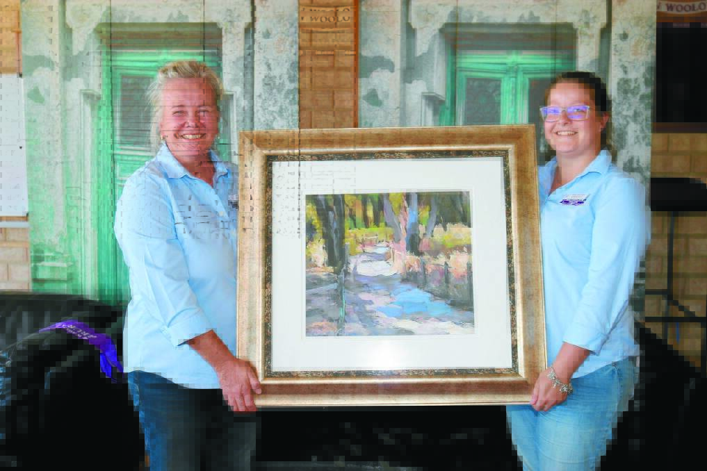 Wagin Woolorama vice president Fiona Dawson (left) and marketing, media and administration assistant Jemma Bell with last years overall winning artwork Peaceful track by Carmen McFall, Dunsborough.