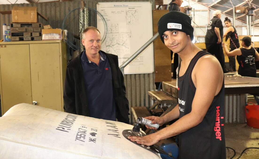 Western Australia Shearing Industry Association representative and Moora shearing contractor Brad Butcher watches as Sheldon Barron, 20, of Moora, inks stencils identifying the bale of wool shorn and prepared by the shearing and wool handling school.