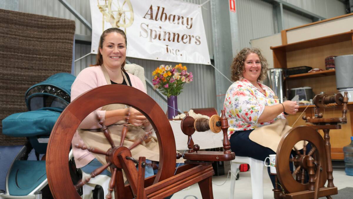 Albany Spinners Inc president Leeza McLean (left) and vice president Marisha Stone, both Albany, were hard at work spinning wool from a donated Melanian fleece as part of their group's display.