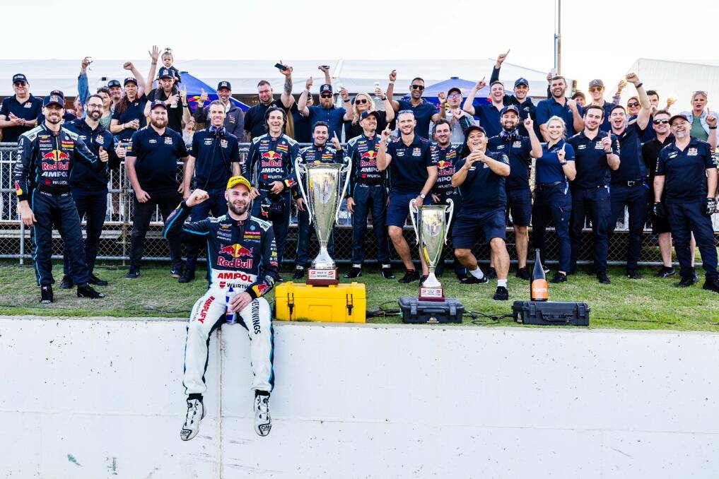New Holland service parts technician Daniel Just (third left front), celebrates with the Red Bull Ampol Racing pit crew and driver Shane van Gisbergen (seated, front).