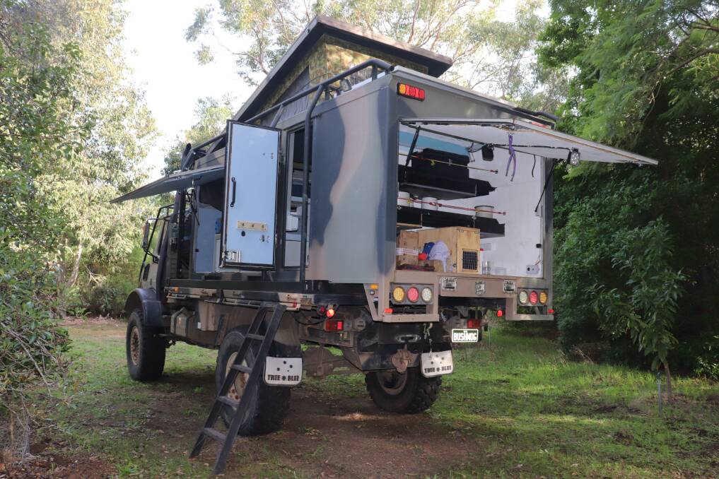 A view of the Unimog with the rear camper doors and roof open and the specially designed ladder for easy access.