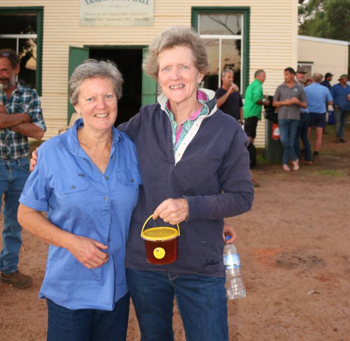 Raelene Spencer (left) and Anne Mitchell, Mingenew, hold up the door prize of honey kindly donated by an ex-Mingenew farmer.
