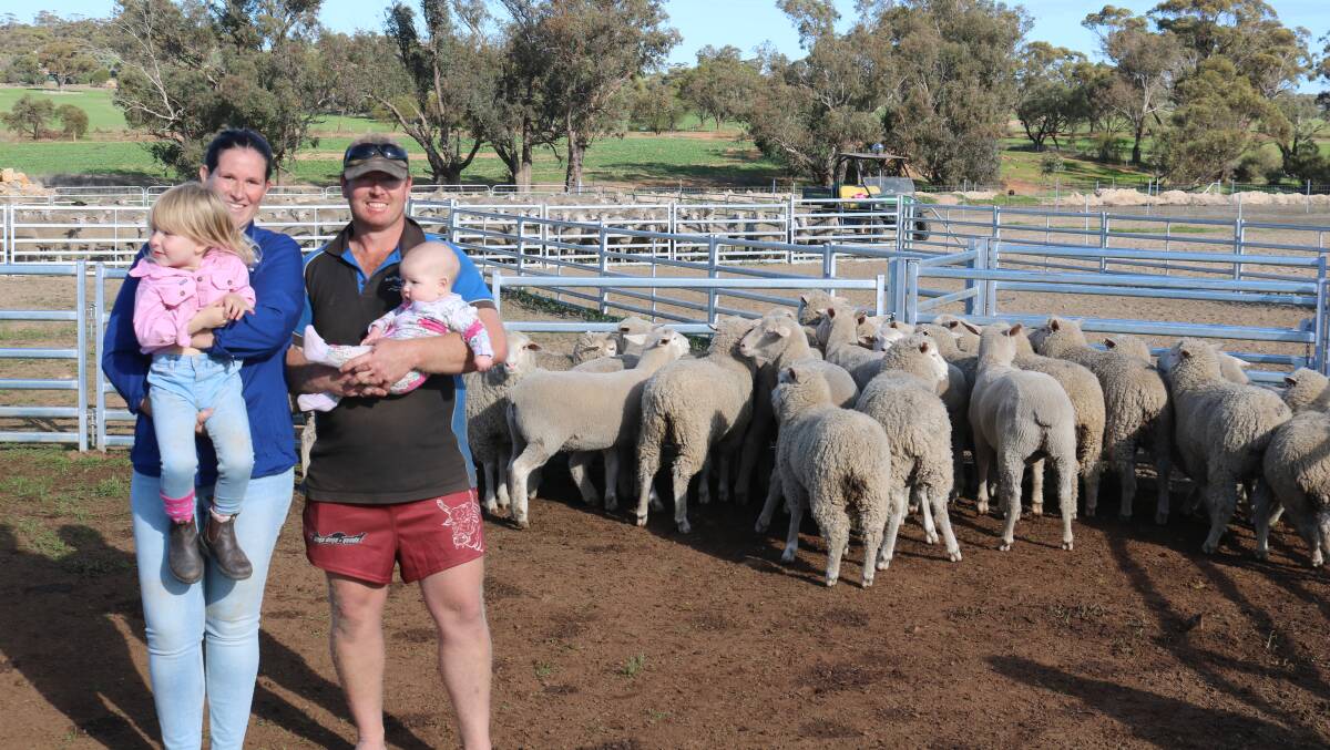 Toni Wallace, with three-year-old daughter Lexi and husband James holding Wrenlee, five months, with some of the lambs they produce in their feedlot. Mr Wallace is the fourth generation of the Wallace family to farm at Gwambygine.