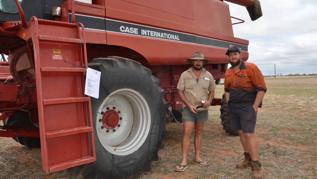 Luke Higgins (left), Merredin and Ryan Butcher, Mukinbudin, with the smaller of two Case IH Axial Flow combine harvesters with fronts and comb trailers, offered at the sale. Both displayed last years pre-season service report from the local Hutton & Northey branch.