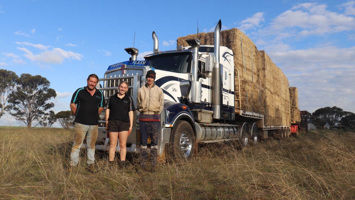 Farmers Across Borders vice chairman Ross Stone (left) loaded the road trains last week with the help of his daughter Annika and volunteer Cameron Fisher.