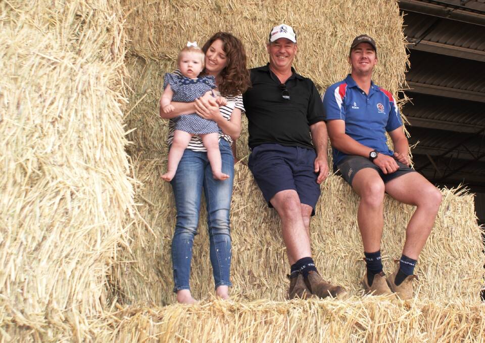  Jeremy James (centre) with daughter Kate Deering holding her 13-month-old daughter Sage and farm leading hand Cameron Finnie with a stack of new seasons' hay at the James' property at Hyden last week. The family was WAMMCO's Producer of the Month for September.