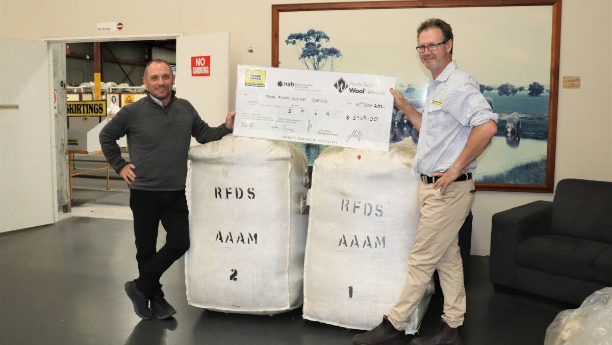 Mr Noa (left), also bid up on two bales of fine wool donated by Dyson Jones Wool Marketing Services. He and Dyson Jones State manager and director Peter Howie hold a cheque for $5969 for the Royal Flying Doctor Service.