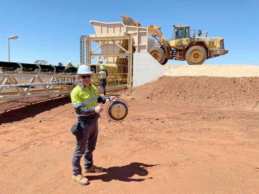 SO4 chief executive officer Tony Swiericzuk rings an Oriental gong to signal the start of commissioning of the front-end feed system for its Sulphate of Potash (SoP) fertiliser plant at Lake Way near Wiluna. On the gong chime the loader behind him tipped the first harvest salts into the feed hopper and a conveyor carried then up to a surge bin and lump breaker. Photos by SO4.
