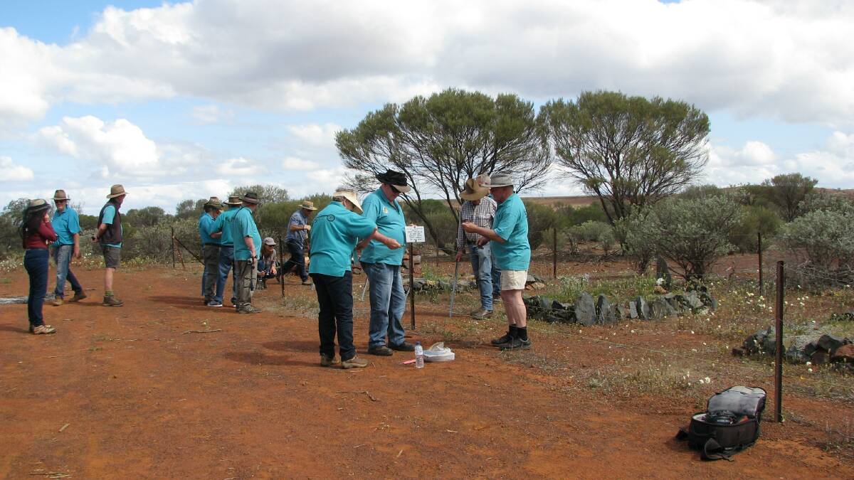 Members of a 4x4 club (in blue shirts) help members of Outback Grave Markers drive in posts and attach plaques in Gullewa cemetery in the Yalgoo shire.