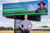 National Farmers' Federation chief executive Tony Mahar in front of the campaign billboard in Canberra, which features sheep and grain farmer Michael Chalmers.