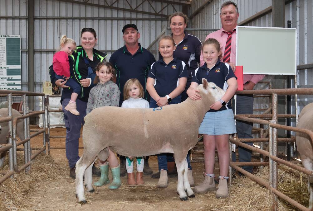 With the $2400 top-priced JimJan Texel sire were buyer Ellen Walker (left), Warranine Park, Brookton, holding daughter Matilda de Gruchy 2, partner Andrew de Gruchy, and their daughters Piper, 7, and Zoe, 4, and JimJan Texel studs Kristy Glover and daughters Ella Robinson, 10, and Josie Robinson, 8, holding the ram and Elders auctioneer Graeme Curry. 