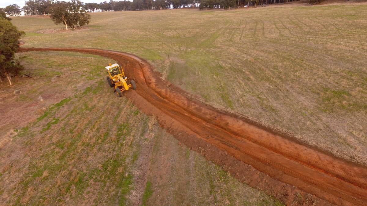 A grader finishes a contour bank by spreading topsoil back over the bank, as part of a landscape rehydration trial at Boyup Brook.