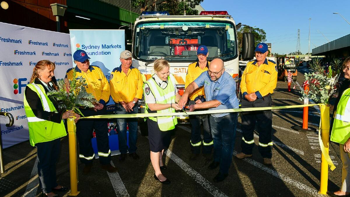 OPEN: Rebel Talbert, NSW RFS assistant commissioner and Carlo Trimboli, chairman, Sydney Markets Foundation officiate the new fire truck handover by cutting the ribbon.
