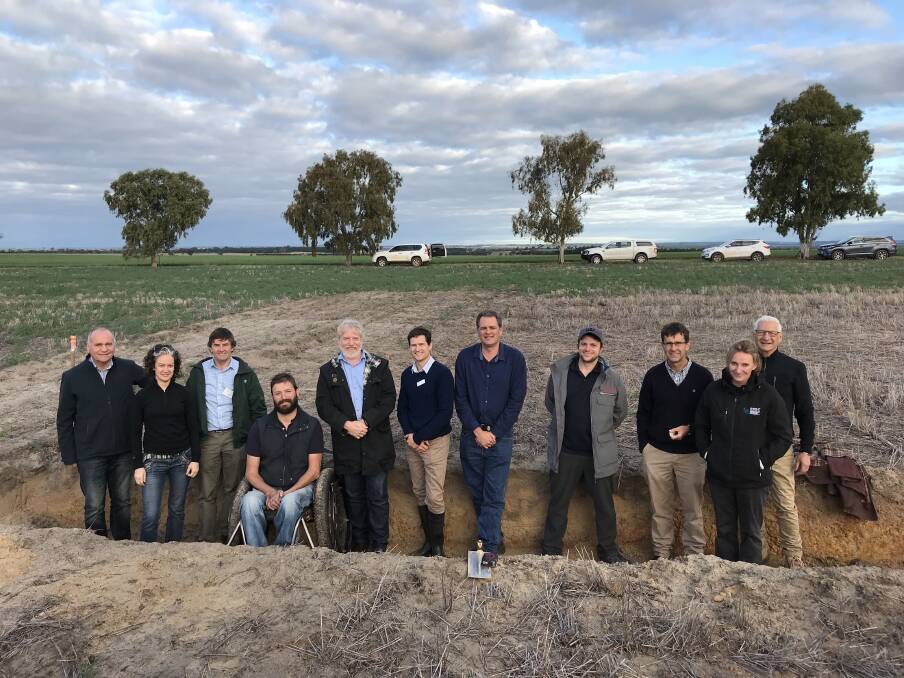 Soils tour participants stand in a soil pit that is looking at the impact of deep ripping on soil movement, at a research site on a property east of Meckering. 
